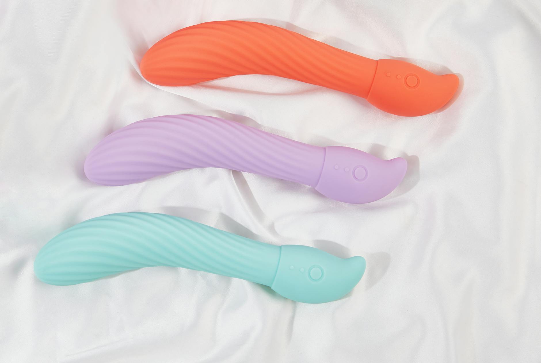 Three colorful clitoral vibrators arranged on white fabric, highlighting different textures and suction styles
