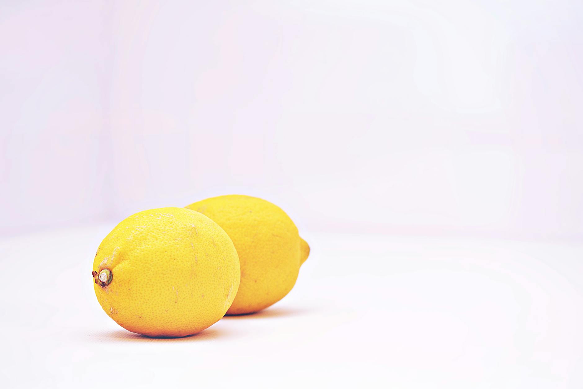Two vibrant lemons on a white background, symbolizing renewal and fresh sensation.