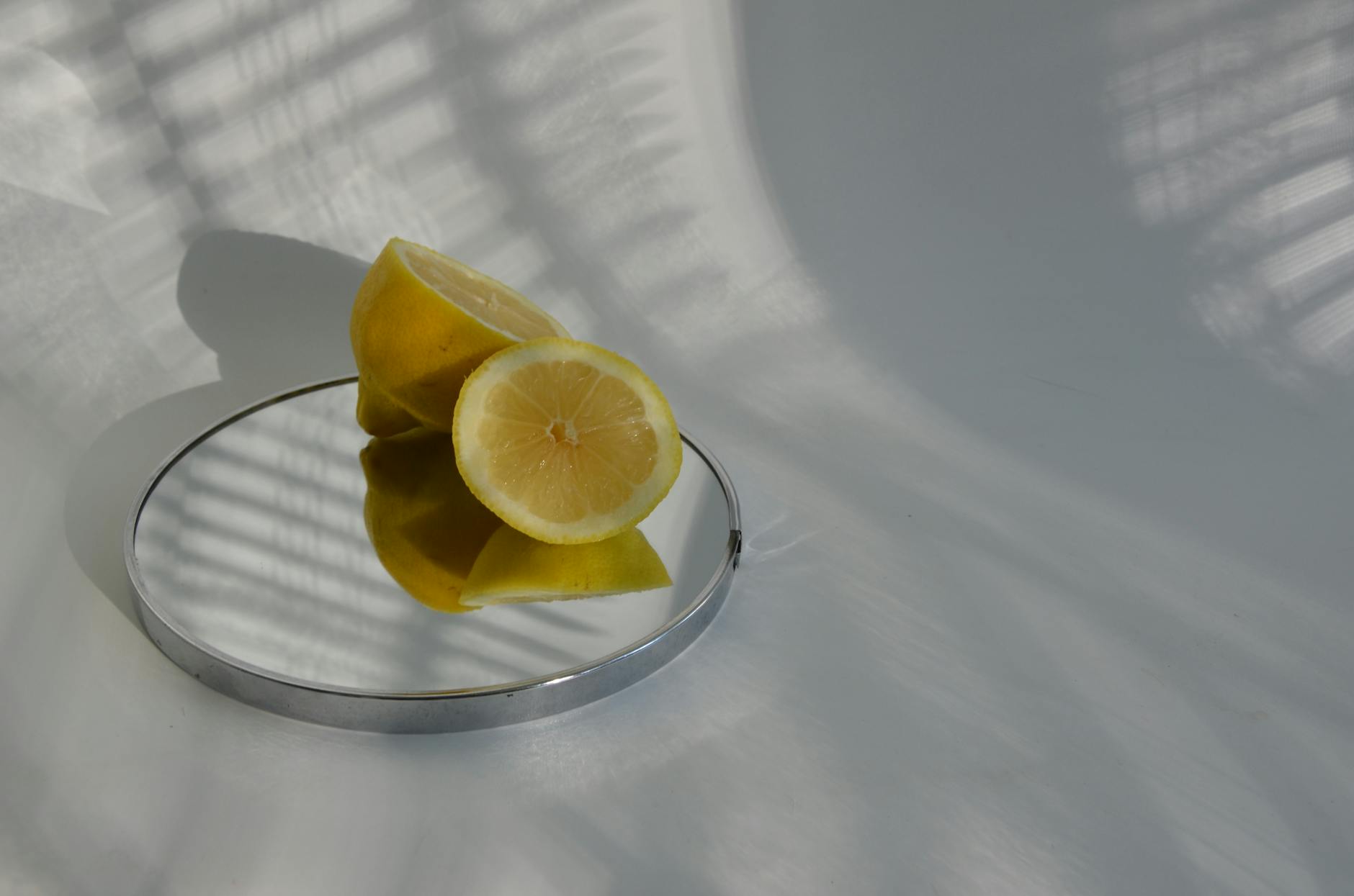Limones cortados en espejo proyectando sombras, mostrando fotografía minimalista de alimentos