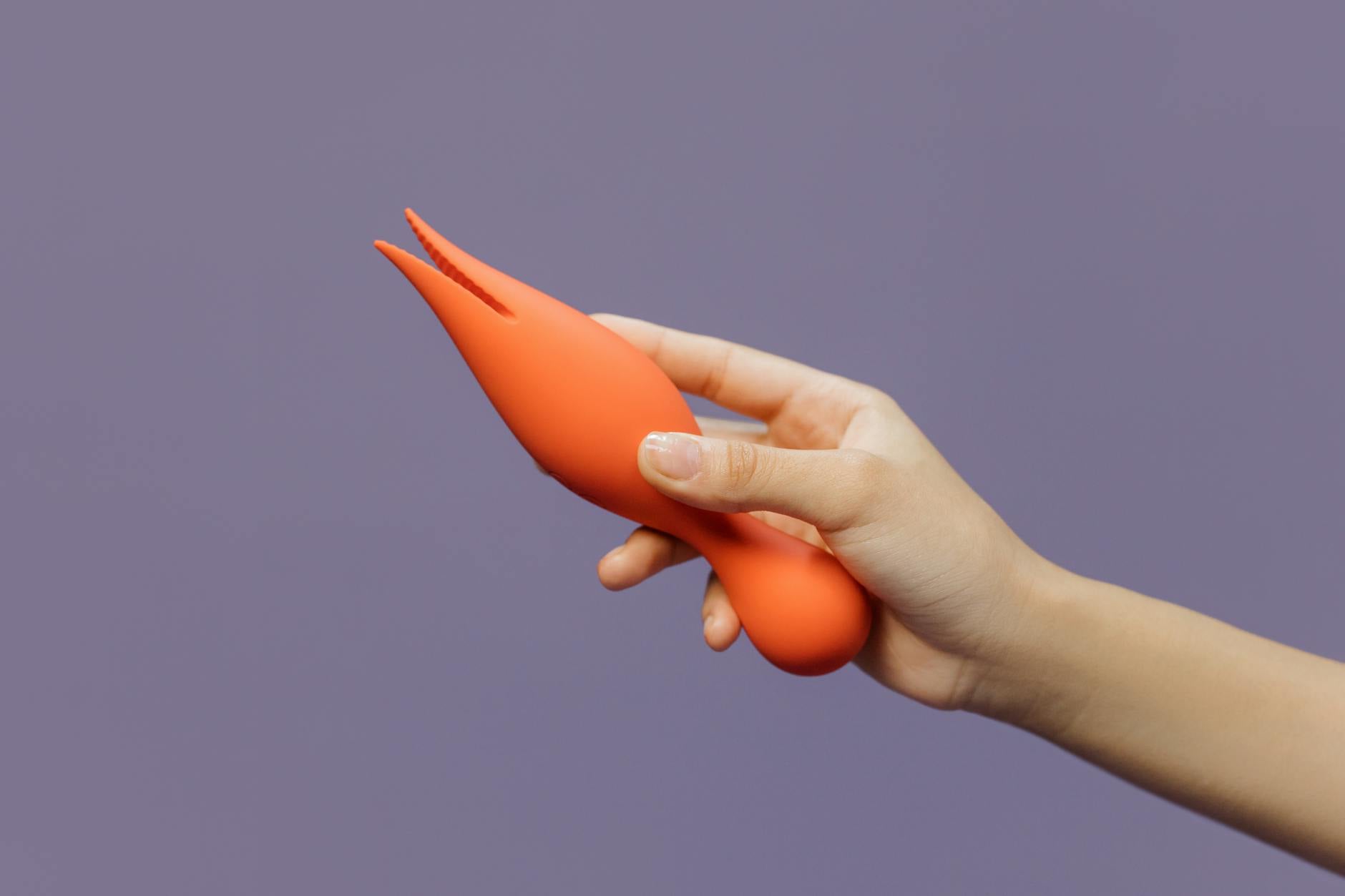 A close-up of a hand holding a lemon vibrator against a minimalistic purple backdrop, showcasing modern sensuality and control