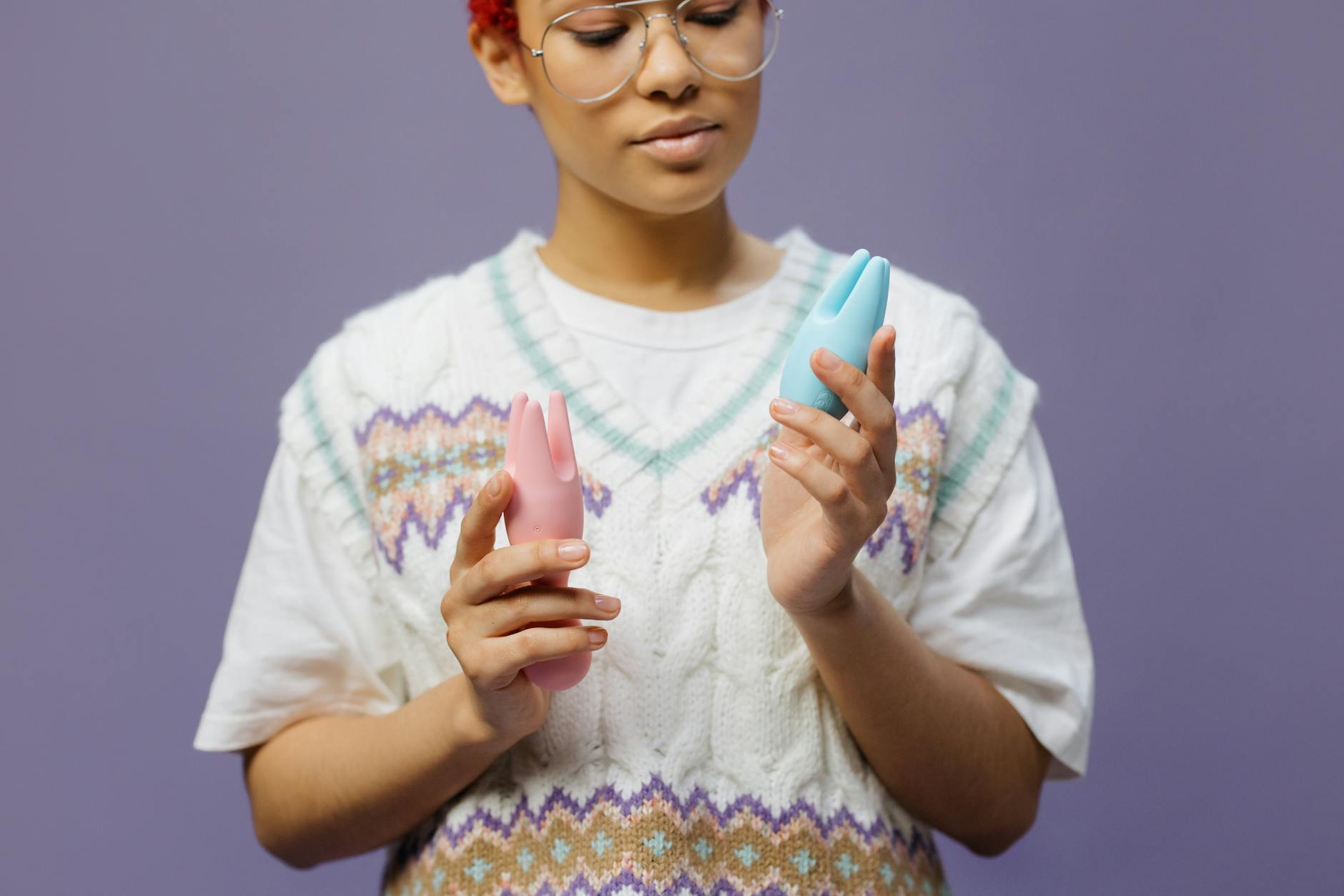 Mujer con anteojos sosteniendo un vibrador de silicona azul y rosa en actitud contemplativa