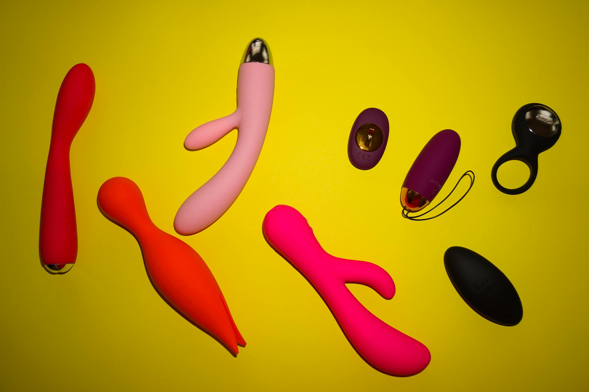 Mano sosteniendo un vibrador naranja moderno contra un fondo púrpura minimalista
