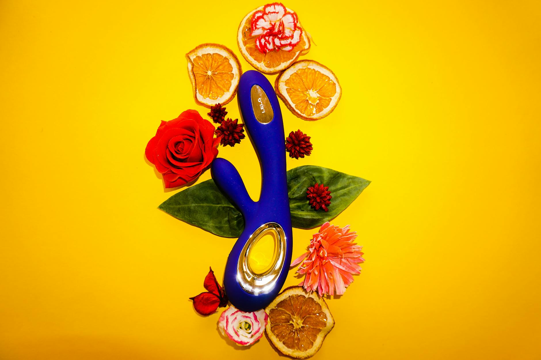 A blue lemon vibrator surrounded by flowers and citrus slices on a bright yellow background