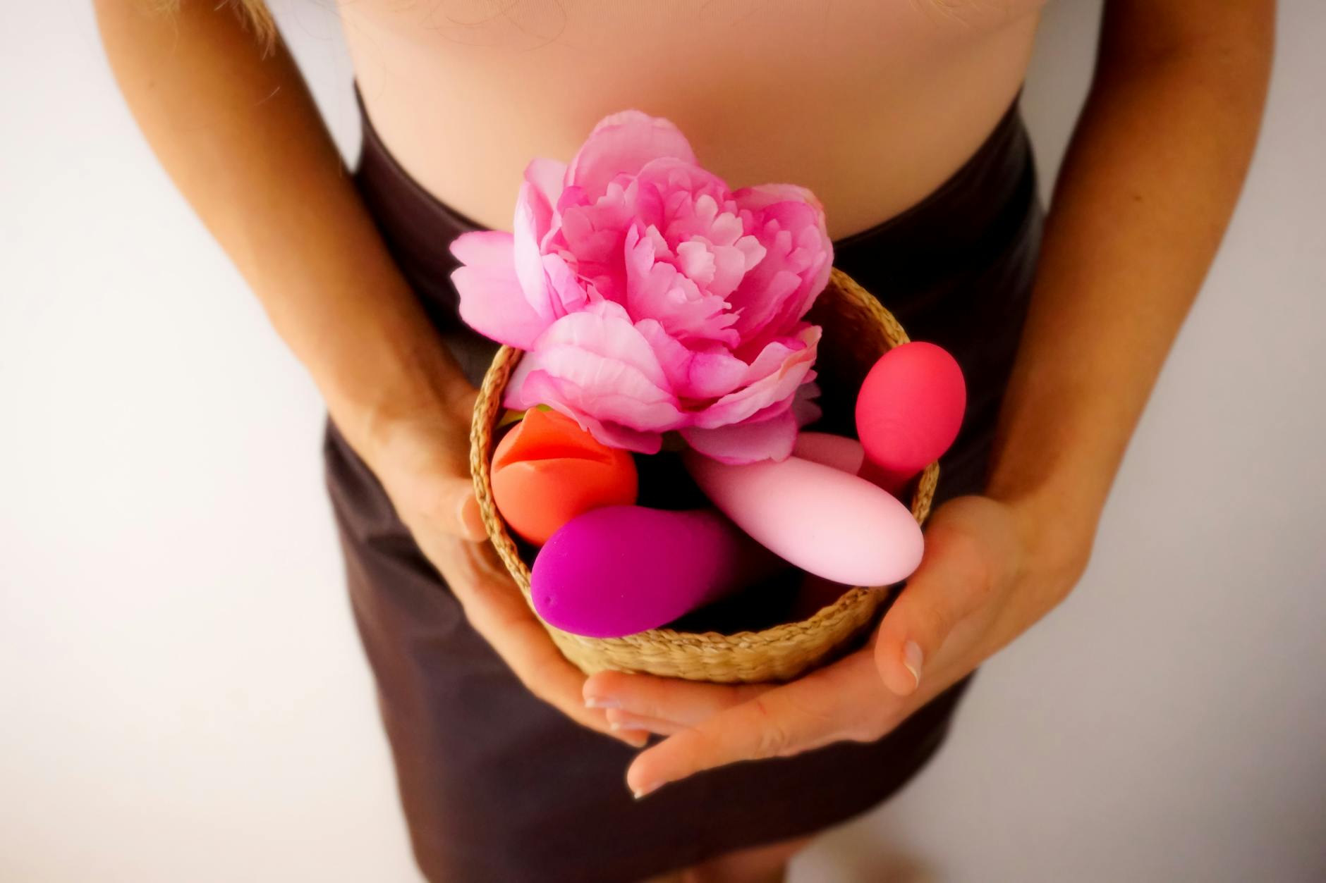 A woman holding colorful vibrators against a purple background