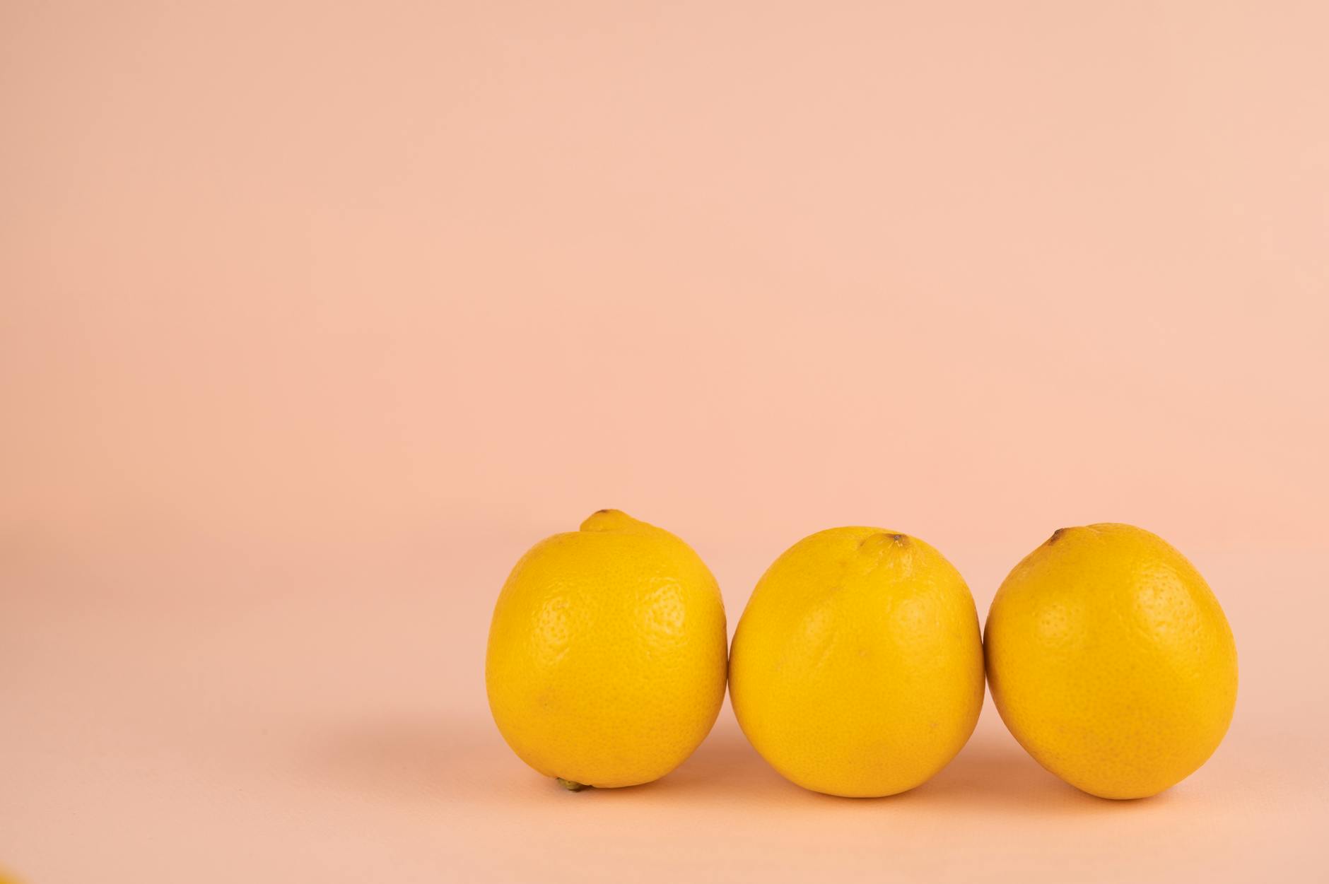 Fresh lemons halved on a pink background, symbolizing natural healing and gentle restoration